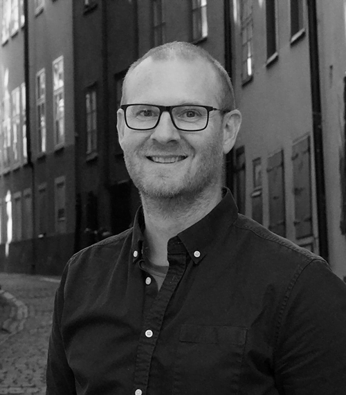 Porträtt av man med glasögon i svartvitt på gata